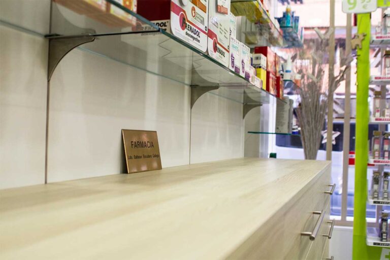 Paneles de madera con estantes regulables y almacenaje inferior para farmacias.